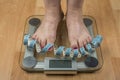 A woman stands with two feet on a scale. Overweight concept