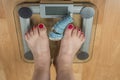 A woman stands with two feet on a scale. Overweight concept