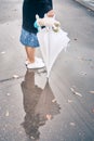 Woman stands under an umbrella in the rain. in puddles reflection. young yawner is holding a stuffed toy