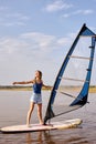 woman stands on windsurf and holds the sail. Windsurfing on lake water, relaxing on water.