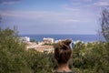 A woman stares into the distance to the sea horizon and the city in front of him