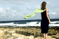 Woman staying on the seashore with shawl behind