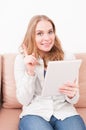Woman staying on sofa maiking idea gesture holding tablet