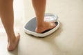 Woman stepping on floor scales. Overweight problem