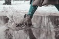 A woman steps into a puddle. Splashes of water scatter from under the feet
