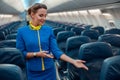 Woman stewardess pointing at passenger seat in airplane cabin Royalty Free Stock Photo