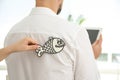 Woman sticking paper fish to colleague`s back in office. April fool`s day