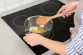 Woman stirring butter in saucepan on electric stove