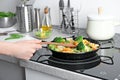 Woman stirring frozen vegetables on frying pan