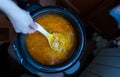 Woman stirring with a plastic scoop the soup with meatballs cooked in a slow cooker Royalty Free Stock Photo