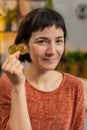 Woman stock trader holding two golden bitcoins BTC, looking at camera increasing wealth at home