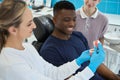 Woman stomatologist showing to male client work of jaw and teeth