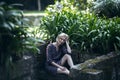 A woman on a stone bench among the greenery in an old park, Porto, Portugal. Royalty Free Stock Photo