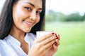 That woman stood happily drinking coffee on the meadow