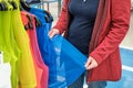 Woman in store chooses a bright reflective cape for clothes. Hands close up shot