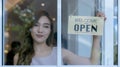 Woman store owner turning open sign broad through the door glass and ready to service. Small business woman owner turning the sign Royalty Free Stock Photo