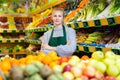 Woman store worker in apron at fruit department of supermarket