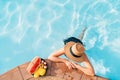 Woman in straw hat and bikini in sunglasses at swimming pool enjoying fresh tropical fruits