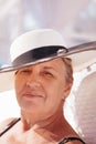 A woman in a straw hat. Close-up portrait of an elderly, happy woman in a white straw hat resting in a hotel on summer