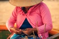 Woman in Straw Hat Hiding Face Mends Fishing Net on Beach