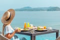 Woman in straw hat near swimming pool, eating food and enjoy ocean view