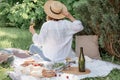 Woman in straw hat on picnic holding a glass of wine from behind. Summer time adventures Royalty Free Stock Photo