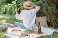 Woman in straw hat on picnic holding a glass of wine from behind. Summer time adventures Royalty Free Stock Photo