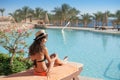 Woman in a straw hat relaxing on a daybed near a luxurious summer pool hotel Egypt, concept time to travel Royalty Free Stock Photo