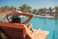 Woman in a straw hat relaxing on a daybed near a luxurious summer pool hotel Egypt, concept time to travel Royalty Free Stock Photo