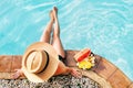 Woman in straw hat sitting on swimming pool side with plate of tropical fruits- camera top view