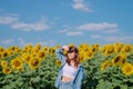 A woman in a straw hat is standing in a large field of sunflowers. stands in flowering field. Summer time, lifestyle, travel and Royalty Free Stock Photo