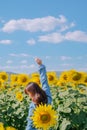 A woman in a straw hat is standing in a large field of sunflowers. stands in flowering field. Summer time, lifestyle, travel and Royalty Free Stock Photo