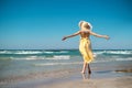 Woman with straw hat and yellow dress on the beach and arms streched Royalty Free Stock Photo