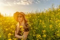 Woman in straw sun hat enjoying spring in yellow flowers field.Summer concept lifestyle female against sunset golden light in Royalty Free Stock Photo