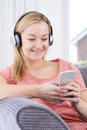 Woman Streams Music From Mobile Phone To Wireless Headphones Royalty Free Stock Photo