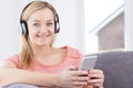 Woman Streams Music From Mobile Phone To Wireless Headphones Royalty Free Stock Photo