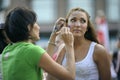 Woman street artist making face painting for a little girl using brush Royalty Free Stock Photo