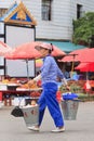 Woman on the street carrying two buckets in Ruili, Yunnan Province, China