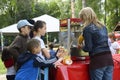 Woman street seller selling fast food for children standing in a line in front of a food moving store