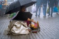 Woman street side vendor hiding under large umbrella selling corn on cob to tourists