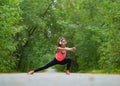 Woman stretch muscles at park before jogging. Athletic exercising outdoor.