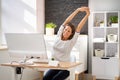 Woman Stretches At Office Desk