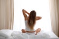 Woman stretching in bed after wake up, back view, entering a day happy and relaxed after good night sleep. Sweet dreams Royalty Free Stock Photo