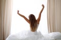 Woman stretching in bed after wake up, back view, entering a day happy and relaxed after good night sleep. Sweet dreams Royalty Free Stock Photo