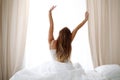 Woman stretching in bed after wake up, back view, entering a day happy and relaxed after good night sleep. Sweet dreams Royalty Free Stock Photo