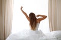 Woman stretching in bed after wake up, back view, entering a day happy and relaxed after good night sleep. Sweet dreams Royalty Free Stock Photo