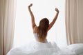 Woman stretching in bed after wake up, back view, entering a day happy and relaxed after good night sleep. Sweet dreams