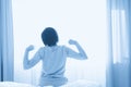 Woman stretching in bed after wake up in front of window, back view Royalty Free Stock Photo