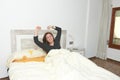 Woman stretching in bed after waking up.