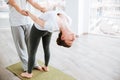 Woman stretching and doing acro yoga with partner in studio
